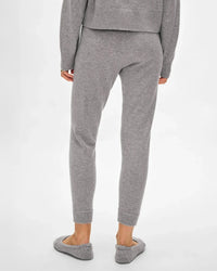 A person faces away wearing White + Warren's Cashmere Jogger in Grey Heather with a relaxed fit, paired with a matching long-sleeve top and gray slippers, set against a plain white background.