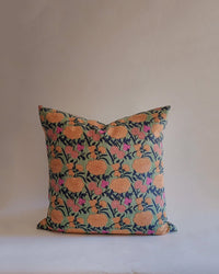 The Nargis Linen Pillow by Soil to Studio (18 x 18 in, Sage) showcases a floral Valley of Flowers-inspired design in orange, pink, and green on a dark background, set against a plain light backdrop.