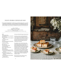 A recipe page for Vegalicious Cheesecakes – Bakery-Style & Plant-Based by Cozy Publishing appears beside a photo of these plant-based treats on vintage plates, set on a rustic table with white flowers in the background.