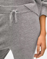 A person wears the White + Warren Cashmere Jogger in Grey Heather, featuring a drawstring waist. The image highlights the soft cashmere fabric and relaxed fit, focusing on the waist and arm for a cozy look.