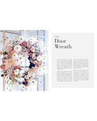 An elegant floral wreath with white and blush flowers, inspired by Joseph Massie’s style, hangs on a glass door next to a text block titled "The Flower School" by Chronicle Books, set against a white background.
