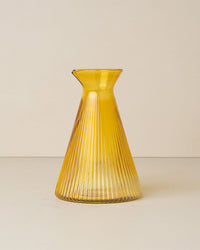 The Saarde Kairos Angular Carafe in Yellow Topaz features ribbed, durable borosilicate glass with a narrow neck and flared rim, shown against a plain, light background.