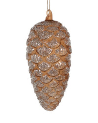 The Cody Foster Forest Floor Pinecone in Dark Brown ornament, adorned with silver glitter, hangs by a string against a plain white background.