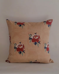 The Babita Linen Pillow (22x22 in Red) from Soil to Studio features a beige background with red and pink floral patterns and green leaves, inspired by the Valley of Flowers, shown against a simple, light backdrop.
