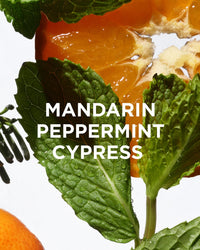 Close-up of fresh mint leaves with water droplets, a partially peeled mandarin orange, and a cypress branch evokes the refreshing essence of hydrating skincare, featuring Rosie Jane Chill Body + Bath Oil with "MANDARIN PEPPERMINT CYPRESS" in white text.
