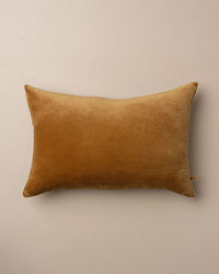 The Saarde Velvet Lumbar Pillow with Feather Insert in Nutmeg is placed at the center of a plain light beige background.