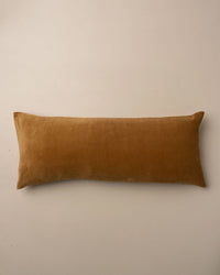 The Saarde Velvet Body Pillow with Feather Insert in Nutmeg is displayed on a plain, light-colored surface.