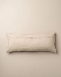 The Saarde Velvet Body Pillow with Feather Insert in Nutmeg rests against a plain light-colored wall.