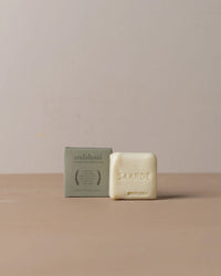 A bar of Saarde Olive Oil Bar Soap in Andalusia sits beside its green cardboard packaging on a plain beige surface with a light background.