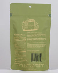The back of a green Wildflower Caramel Co Dark Chocolate Sea Salt Caramels in A Bag shows nutritional facts, ingredients, company info, barcode, and states the product is handmade and sustainably sourced in San Antonio, TX with fair trade caramels.
