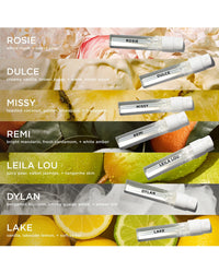 Six labeled vials from the Rosie Jane Fragrance Discovery Set are displayed diagonally on a vibrant backdrop of fruit, flowers, and leaves. Each clean perfume’s name and scent notes appear beside its bottle.