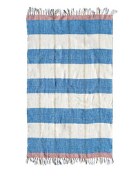 The Suave Aire - Blanket Roll by caminito features horizontal blue and off-white stripes with pink bands at each end, fringed edges, and a slightly rough, handwoven texture reminiscent of natural fiber blankets.