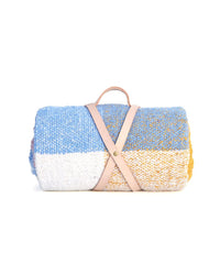 The caminito Suave Campo - Blanket Roll features blue, white, and yellow color blocks, handwoven in Mexico and rolled up with a tan leather strap and handle, shown against a white background.