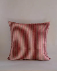 The Babita Linen Pillow - 22 x 22 in Red by Soil to Studio features red and white vertical stripes inspired by the Valley of Flowers, shown against a plain, light-colored background.