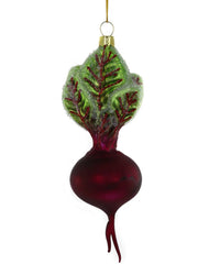 The Small Heirloom Beet Ornament by Cody Foster is a hand-crafted Christmas decoration featuring a deep red beet with green leaves, glitter accents, and red veins, hanging elegantly from a gold string.