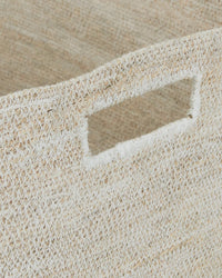 Close-up of the Essential Woven Storage - Square Basket by Hawkins New York, crafted from natural fibers with a rectangular cut-out handle and a light, textured finish—an elegant and practical storage solution.