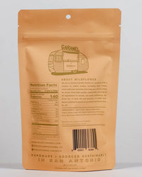 Tan resealable bag featuring a sketched camper and "Maple Whiskey Caramels" at the top. Wildflower Caramel Co—a Texas-based, women-owned company—features nutrition facts and sourcing info on the back.