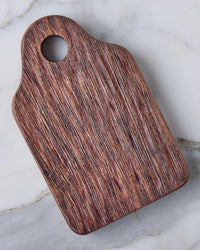 The etúHOME Dutch Small Cheese Board w/ Spreader in Natural, featuring a handle and round hole, is displayed on a light marble surface—an ideal and stylish hostess gift.