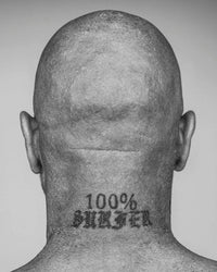 A monochrome portrait from Surf Tribe by Simon & Schuster shows the back of a bald head and neck with a "100% SURFER" tattoo, embodying surf culture in stark black and white.
