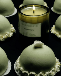 The Flamingo Estate Prinsesstarta Candle fills the air with a sweet almond marzipan aroma, inspired by dome-shaped green cakes topped with white cream and delicate flowers, perfect for brightening any dark surface.