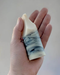 A hand holds the Erode Soap Mini in Jasmine Ylang Ylang by Ume Studio, featuring a white and blue marbled design with a tapered tip, set against a neutral background.