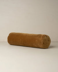 The Saarde Velvet Structured Bolster in Nutmeg, featuring a soft, velvety texture, rests on a light surface with a neutral background.