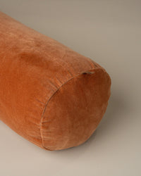 A close-up of the Saarde Velvet Structured Bolster in Terracotta, featuring a round design and plush velvet texture, set against a neutral background.