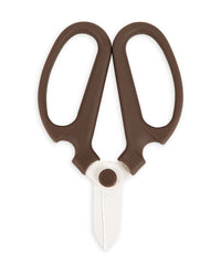 The Floral Society’s Japanese Floral Clippers in Peat, featuring wide brown handles and short white blades, are displayed open on a white background, their design forming an owl-like face.