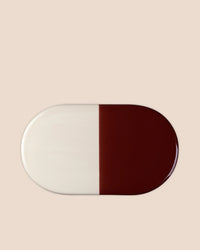 The Bergs Potter Nuna Glazed 13.4 x 7.9 Tray in Sandstone/Deep Burgundy features a food-safe, rectangular ceramic design with rounded edges and two equal color halves, crafted from durable glazed stoneware.