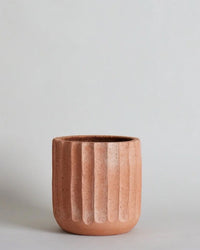 The Fluted Planter | Large by Bloomist, a cylindrical handmade terracotta planter with vertical ridges, sits on a plain light grey background.
