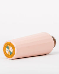 The 25oz Hemingway Flask by Business & Pleasure Co in Dusty Pink, a light pink cylindrical water bottle with vacuum insulation, rests on its side. Its base displays a geometric logo, set against a plain white background.