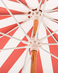Close-up view from underneath the Amalfi Umbrella - Crew Le Sirenuse Stripe by Business & Pleasure Co, a red and white striped umbrella with a wooden pole, white spokes, and UV resistant fabric in a bold radial pattern.