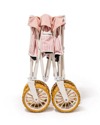 The Beach Cart - Laurens Pink Stripe by Business & Pleasure Co features large yellow sand wheels and a pink and white striped seat, and is shown compactly folded, standing upright on a white background.