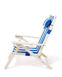 The Tommy Chair by Business & Pleasure Co features a white acacia wood frame with armrests, a blue and white Mediterranean Stripe canvas sling seat and backrest, and a matching striped pillow attached near the top.