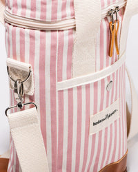 A close-up of the Wine Cooler Tote Bag - Laurens Pink Stripe by Business & Pleasure Co, featuring pink and white stripes, cream straps, vegan leather zipper pulls, and a branded front pocket label.