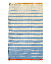 The caminito Marea Paseo - Blanket Roll is a handwoven, rectangular picnic blanket featuring blue and off-white stripes with thin orange borders, offering a textured look ideal for both indoor and outdoor use. Made in Mexico.