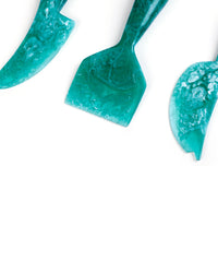 Casa Amarosa’s Resin Cheese Knife Set of 3 in Green is partially shown on a white background—the perfect handmade set for your charcuterie board.