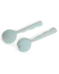 The Casa Amarosa Resin Salad Server Set in Sky Blue includes two handmade servers from India—one spoon and one forked—each featuring rounded, light blue marbled resin handles.