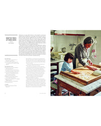 A woman and child roll pasta dough together in their kitchen, inspired by recipes from Pasta Grannies: The Official Cookbook by Chronicle Books, with utensils and a sink visible in the background.
