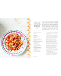 A bowl of tagliatelle in tomato-anchovy sauce sits on a patterned plate beside a recipe page, echoing the cherished recipes found in Pasta Grannies: The Official Cookbook by Chronicle Books.