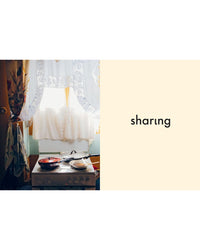 The “Yiayia” cookbook from Chronicle Books, featuring vegetarian Greek dishes, is displayed beneath a lace-curtained window; the word “sharing” appears on a beige background next to the scene.