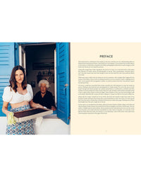 A woman holding a baking tray stands by an open blue window as an older woman smiles from inside, capturing the warmth of Greek cooking. The book Yiayia from Chronicle Books features a preface printed on the right side of the image.