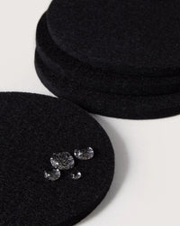 The graf lantz Bierfilzl Merino Wool Felt Round Coaster Solid in Black (4 Pack) adds an elegant, sustainable touch to your décor, shown here on a white surface with water droplets highlighting its absorbent design.