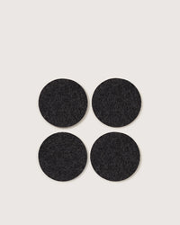 A set of four round Bierfilzl Merino Wool Felt Coasters in solid charcoal by graf lantz is arranged on a light background, offering a stylish and sustainable touch to any home decor.