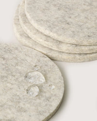 Close-up of graf lantz Bierfilzl Merino Wool Felt Round Coaster Solid in Heather White (4 Pack), showing water beading on the surface—a stylish and sustainable accent for your home.