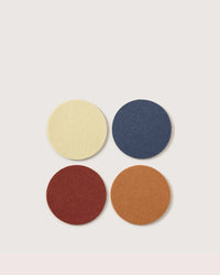 The graf lantz Bierfilzl Merino Wool Round Coaster Multi in Yucca - 4 Pack features four vibrant coasters in yellow, blue, red, and orange, sustainably crafted from premium German Merino wool for a stylish accent.