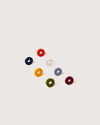 Eight colorful, circular Happy Wine-Ote’s Merino Wool Felt Wine Marker Note Cards by graf lantz are loosely arranged on a plain, light background.