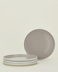Four Essential Dinner Plates in Light Grey by Hawkins New York; three are stacked, one stands behind. The stoneware plates feature a subtle concentric circle pattern. Set of 4.