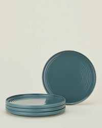 A set of 4 Hawkins New York Essential Dinner Plates in Peacock are stacked, with one plate propped upright behind the stack, all set against a plain light background.