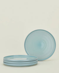 A set of four Hawkins New York Essential Dinner Plates in Sky; three plates are stacked, with a fourth plate standing vertically behind the stack.